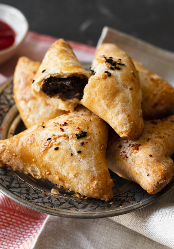 A close-up of a crispy golden samosa with flaky pastry.