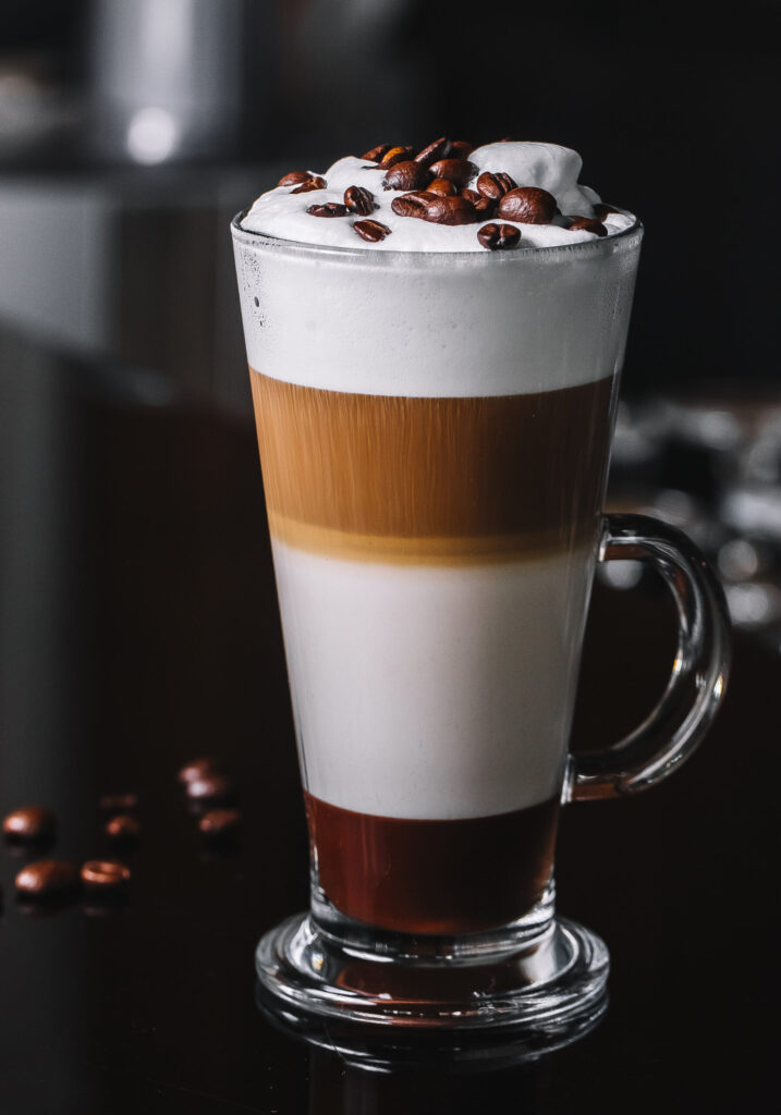 A tall glass filled with a creamy milkshake topped with whipped cream and a straw.