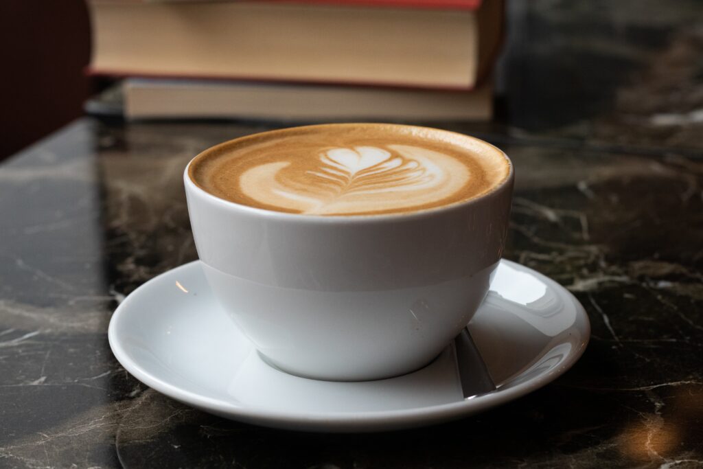 Refreshing latte coffee in a white glass with creamy froth on top.