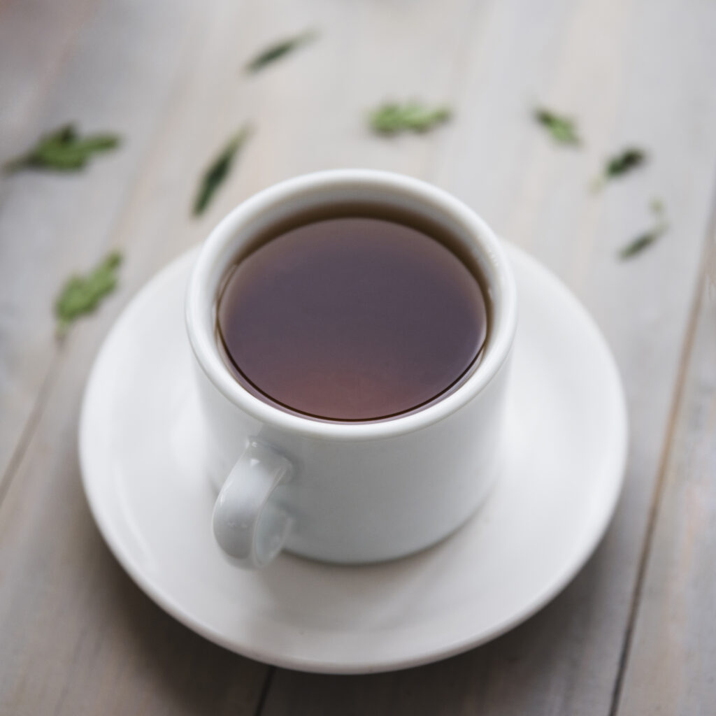 A porcelain teacup filled with hot tea, placed on a matching saucer.